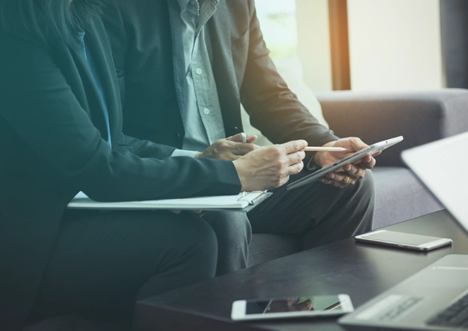 Young business managers collaborating on a new startup project. Laptops on wooden table, typing keyboards, texting messages, and analyzing graph plans.