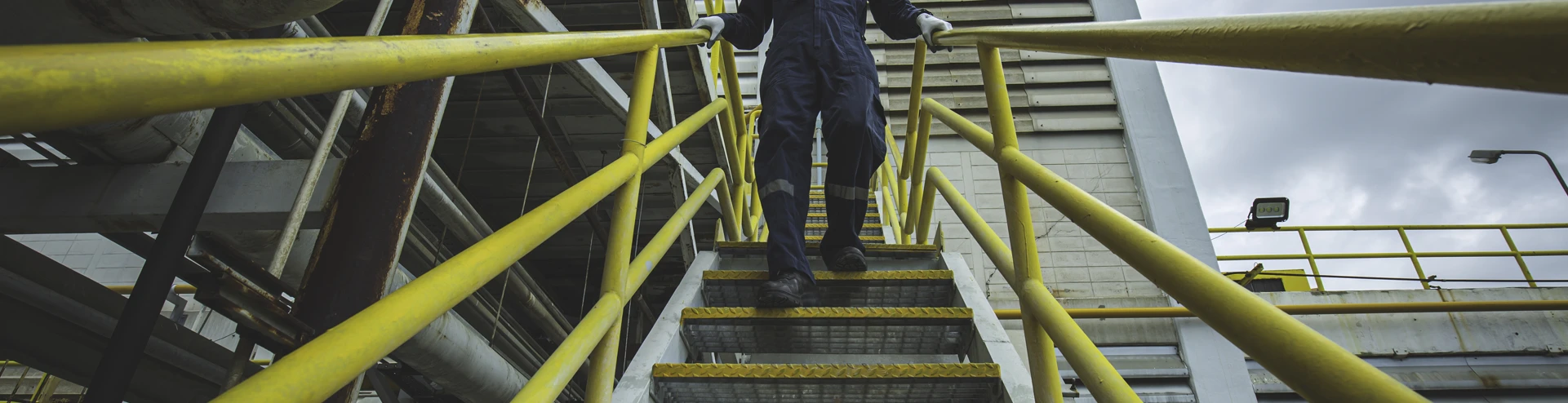 A male worker walking down the stairway during a visual inspection in a factory - emphasizing industrial safety and workflow efficiency.