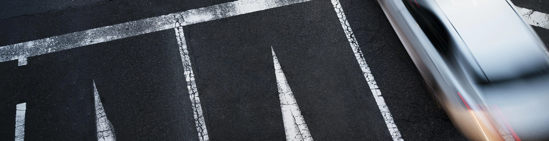 Close-up view of cars crossing a road in a busy urban area, depicting traffic congestion and city life.